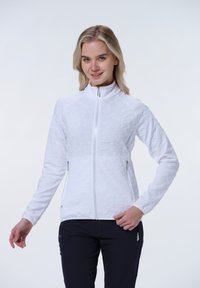 Weiße kurze Jacke mit strukturiertem Muster, hohem Kragen und zwei seitlichen Reißverschluss-Taschen. Lange Ärmel und taillierter Schnitt.