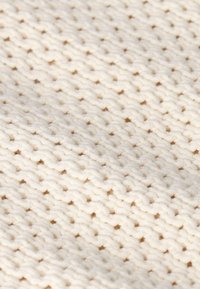 Tissu crème texturé avec un motif de tricot lâche, mettant en valeur un matériau en coton doux et un design tissé uniforme.