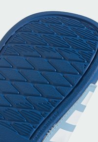 Blå gummisula med texturerat greppmönster som har diamantformer och ribbor. Sidan har ljusblå och vita accenter.