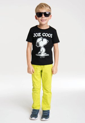 Black t-shirt with "JOE COOL" text and Snoopy graphic, paired with lime green pants and blue sneakers. Sunglasses complete the look.