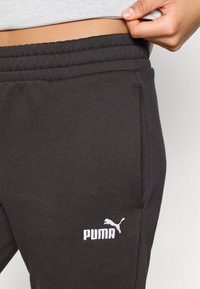 Μαύρο παντελόνι φόρμας με ριμπ ζώνη μέσης, πλαϊνές τσέπες και κεντημένο λευκό λογότυπο Puma στο αρι�στερό μηρό. Μαλακό, υφασμάτινο ύφασμα με υφή.