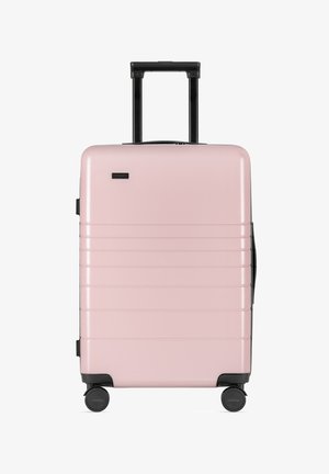 Valigia rigida rosa con superficie texturizzata, scanalature orizzontali, manico telescopico e quattro ruote nere per la mobilità.