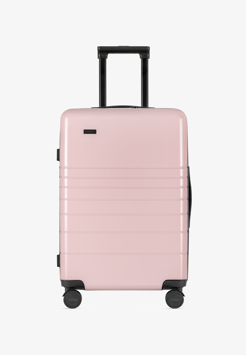 Hartschalen-Koffer in Pink mit strukturierten Oberflächen, horizontalen Rillen, Teleskopgriff und vier schwarzen Rollen für Mobilität.