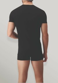Maglietta nera aderente a maniche corte, in tessuto morbido, con design a girocollo, mostrata da dietro, abbinata a pantaloni corti neri.