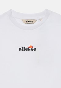 Valge T-särk ümarate kaelustega, millel on rinna keskosas alla krae väikene must ja oranž ellesse logo.