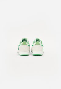 Wildleder- und Stoff-Sneaker in Weiß und Grün. Verfügt über einen gepolsterten Kragen, grüne Akzente und eine weiße Sohle. Die Rückansicht zeigt eine abgerundete Form.