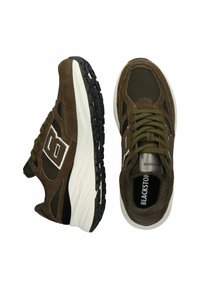 Par de zapatillas de running en marrón y negro con suelas gruesas en blanco, paneles de malla y ante, y cordones verdes, mostradas desde vistas superior y lateral.