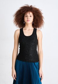 Top senza maniche nero con una texture scintillante, abbinato a una gonna plissettata color teal. L'outfit presenta un collo rotondo e una silhouette aderente.