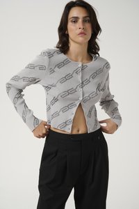 Grey ribbed cardigan featuring a subtle chain pattern, round neckline, and front buttons, paired with black tailored pants.