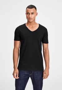 Schwarzes T-Shirt mit kurzem Ärmel und V-Ausschnitt aus weichem Stoff, mit klassischem Schnitt und glatter Textur, kombiniert mit blauen Jeans.