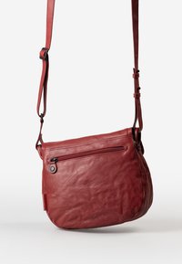Borsa a tracolla rossa in pelle con una superficie morbida e testurizzata, tracolla regolabile e una tasca con zip sulla parte anteriore. Forma arrotondata e design minimal.