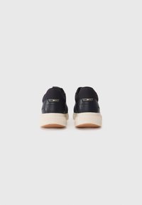 Marineblå sneakers med en glatt læroverdel, mesh-detaljer, en kremfarget gummisåle og diskrète merker på baksiden.