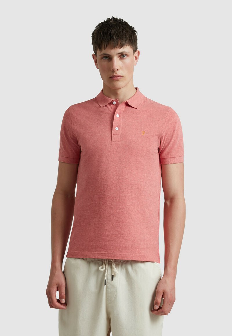 Poloshirt in licht koraal, korte mouwen, gemaakt van een gestructureerde stof. Bevat een drie-knopen knoopsluiting en een klein geel logo op de borst.