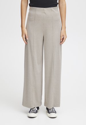 Wide-leg trousers in a light beige houndstooth pattern, featuring a high waist, pleats, and a soft fabric. Paired with black sneakers.