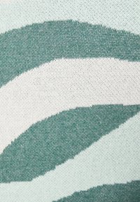 Pletená látka s střídajícími se zakřivenými pruhy v tyrkysové a krémové barvě. Hladká textura s jemným vzorem, rovnoměrně rozloženým po celé ploše.