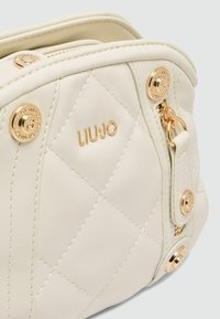 Quilted weißes Lederhandtasche mit goldfarbener Hardware, ausgestattet mit dem Markennamen "LIU JO" und einem Reißverschluss mit seitlichem Clip-Detail.