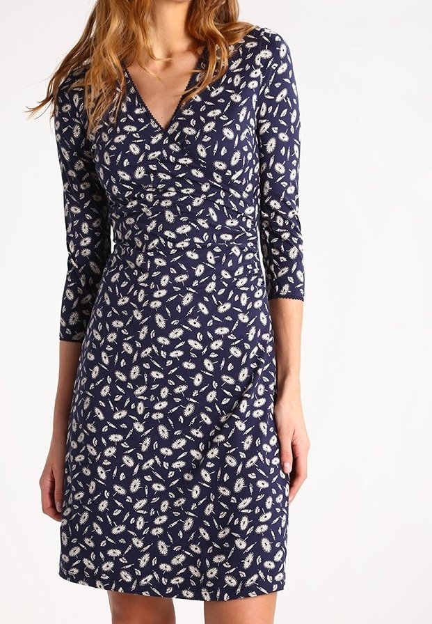 Marinblå klänning med blommönster, trekvartsärmar, V-ringning och figurnära midja. Tillverkad av mjuk, lätt tyg med en slät textur.