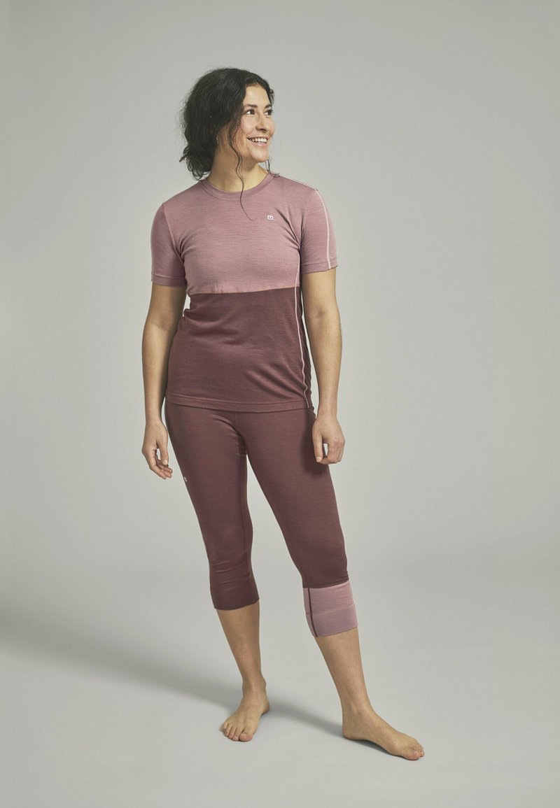 Fitted sports top and leggings in shades of pink and burgundy, short sleeves, knee-length, with a contrasting color block pattern.