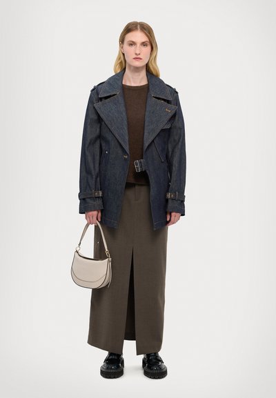 Manteau en denim avec larges revers, haut en tricot marron, jupe olive à fente haute, sac beige clair et chaussures noires à semelle épaisse. Design simple, couleurs neutres.