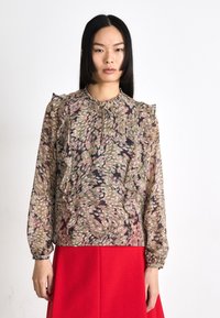 Bluză cu model floral dintr-un material ușor, cu detalii froncate, decolteu rotund și închidere cu șnur. Prezintă nuanțe de bej, roz și accente întunecate.