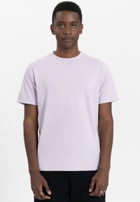 Lichtpaarse katoenen t-shirt met korte mouwen, ronde hals en een minimalistisch ontwerp met subtiele branding op de borst.