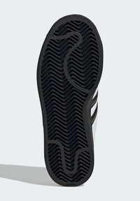 Čierna guma podrážka tenisky so zúbkovaným vzorom. Obsahuje hladký povrch s vyvýšeným logom a kontrastnými bielymi akcentmi.
