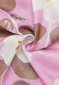 Rosa stof med abstrakte brune og hvide blomstermønstre, med glat tekstur og subtil glans. Stoffet er rullet for at vise designet.