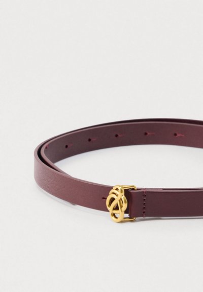 Ζώνη από δέρμα σε μπορντό χρώμα με αγκράφα κόμπου σε χρυσή απόχρωση, με λεία υφή και πολλές τρύπες για ρύθμιση κατά μήκος του λουριού.