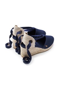 Scarpe con zeppa in tela blu navy con suola in juta intrecciata, caratterizzate da un dettaglio sul tacco intrecciato color cognac e lunghi nastri blu navy per annodare.