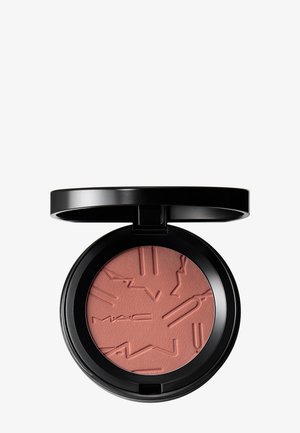 Boîtier compact rond noir avec couvercle ouvert montrant un blush poudre pressée rose poudré embossé de lignes abstraites et marqué "MAC".