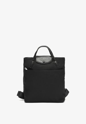 Zwarte nylon rugzak met lederen bovenklep, korte handvatten, voorvak en verstelbare schouderbanden op een witte achtergrond.