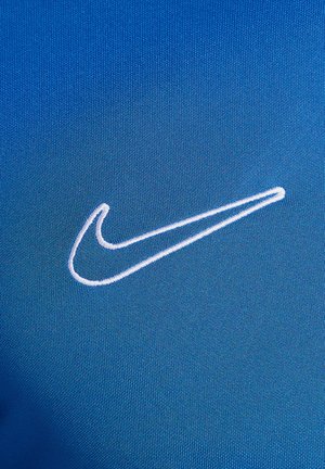 Abbigliamento sportivo Nike in vivace tessuto blu con una fine texture; prominente logo swoosh ricamato in bianco. Il dettaglio ravvicinato mette in mostra la qualità del materiale.