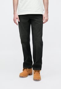 Μαύρα τζιν με ίσια γραμμή και απαλό υλικό, συνδυασμένα με ταμπά δερμάτινες μπότες με χοντρή σόλα και κορδόνια.