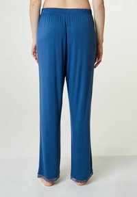 Blauwe pyjamabroek met een relaxte pasvorm, voorzien van een elastische tailleband en kantafwerking aan de hems, gemaakt van zachte, comfortabele stof.