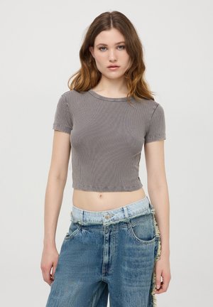 Crop top grigio a coste con maniche corte e scollatura rotonda, abbinato a jeans in denim blu chiaro con taglio irregolare e bordi sfilacciati.