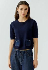 Donkerblauwe short-sleeve trui met een gestructureerde afwerking en twee denim patch pockets. Heeft een ronde halslijn en een relaxed fit.