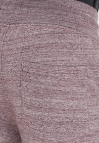 Bordeauxfarbene Fleece-Shorts mit weicher Textur, elastischem Bund und einer einzelnen Gesäßtasche mit einem dezenten melierten Muster.