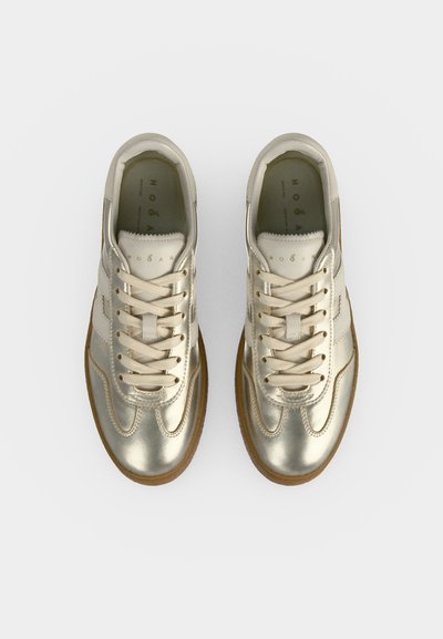 Paire de baskets lacées métalliques dorées avec des accents blancs et des semelles en gomme vues de dessus sur un fond blanc.