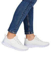 Weiße Sportschuhe mit strukturiertem Strick-Obermaterial, Schnürdesign und gepolsterter weißer Sohle. Kombiniert mit blauen, kurz geschnittenen Jeans.