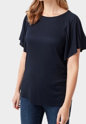 Marineblauw topje met korte, gerimpelde mouwen en een ronde halslijn. Zachte, lichtgewicht stof met een losse pasvorm. Draagt bij een spijkerbroek.