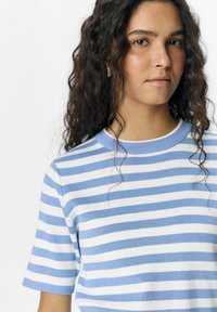 Camiseta de punto a rayas azules y blancas con mangas cortas y cuello redondo, que presenta una textura suave y una silueta ajustada.