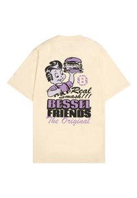 Camiseta de manga corta color crema con un gráfico de un personaje de dibujos animados sosteniendo una hamburguesa, con el texto "Real Smash" y "BESSEL FRIENDS" en colores vivos.
