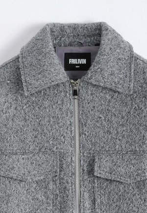 Veste grise texturée avec fermeture éclair, grand col et deux poches avant. L'étiquette indique "FRILIVIN" avec les informations de taille en dessous.