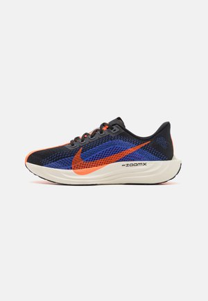 Scarpa da corsa in mesh nera e blu con accenti arancioni, dotata di una spessa suola bianca e dettagli riflettenti. Sistema di allacciatura su un design a profilo basso.
