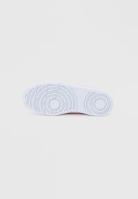 Εξωτερική σόλα αθλητικού παπουτσιού από λευκό καουτσούκ με κυκλικά σχέδια πέλματος και λεία επιφάνεια, με ελαφρύ ροζ τόνο στην άκρη.