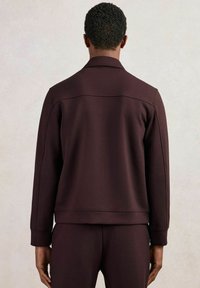 Sweatshirt de culoare burgundă, cu guler standard, manșete și tiv ribbate. Textură moale și cusături minime, conceput pentru o potrivire relaxată.
