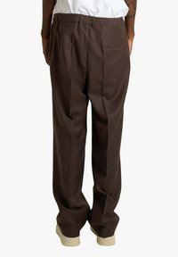 Pantaloni marroni plissettati con vestibilità comoda, vita elasticizzata e dettaglio con tasca posteriore. Il tessuto appare liscio con una leggera lucentezza.