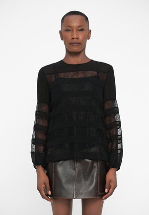 Blusa nera a strati con strisce in pizzo trasparente e maniche lunghe, abbinata a una mini gonna bronzo testurizzata. Tessuto morbido e leggero.