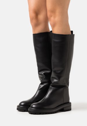Bottes hautes jusqu'au genou en cuir noir avec une texture lisse, un bout arrondi et une semelle à crampons épaisse pour une meilleure adhérence. Présentent un design ample.