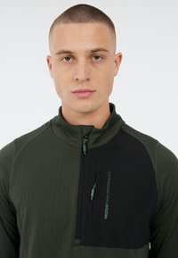 Donkergroene kwart-rits pullover met textuurpatroon en zwarte borstzak. Voorzien van branding "PROTEST HIGH PERFORMANCE" in het groen.